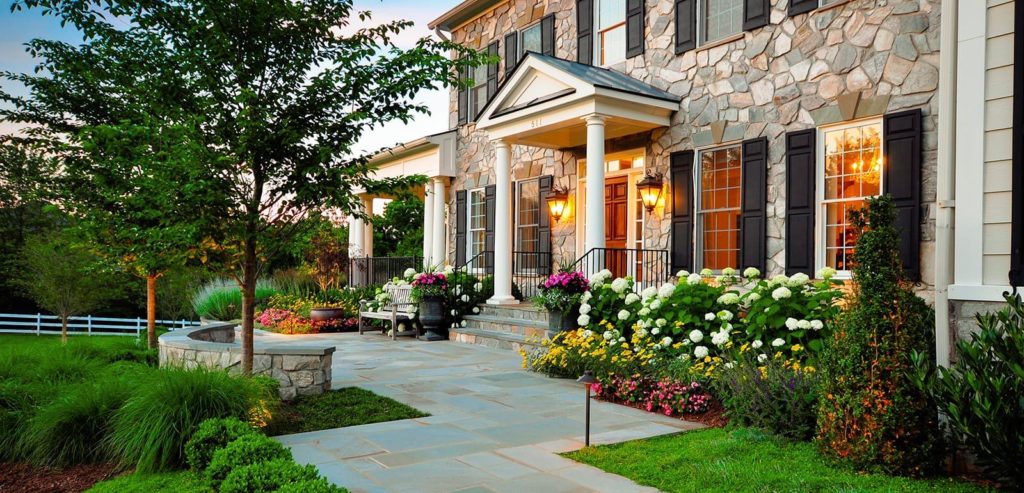 Stone walled house Front Yard Landscaping using different types of plants and a Pathway