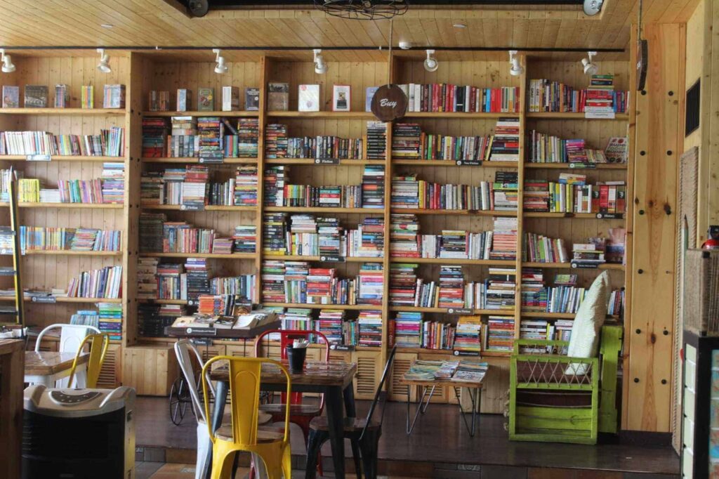 shelves full of books cafe theme with color full chairs and a table