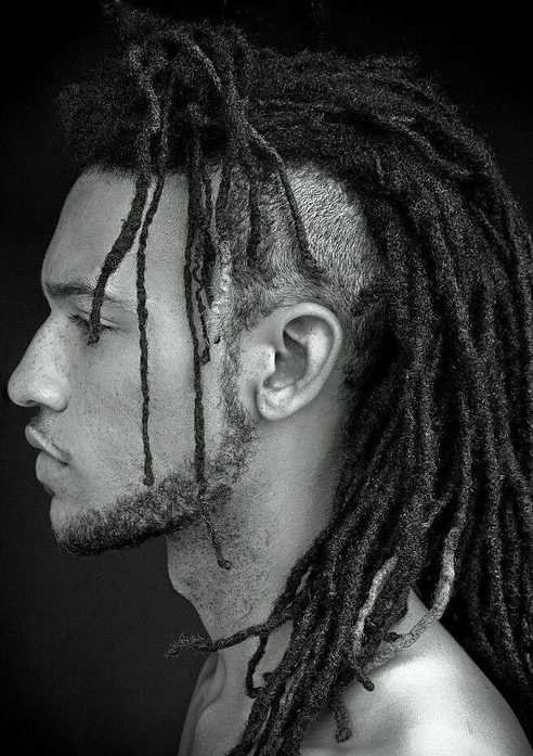 a side face of man showing his Dreadlocks With Pigtails or ponytail in dark Background with black and white tone. 