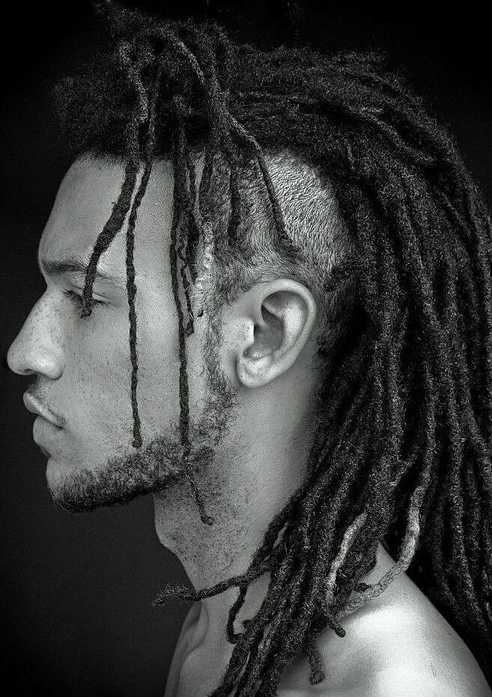 a side face of man showing his Dreadlocks With Pigtails or ponytail in dark Background with black and white tone.