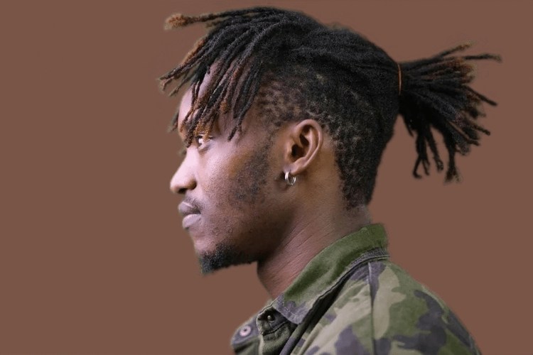0A man with dreadlocks with low ponytail in a camouflage shirt and Solid brown Background
