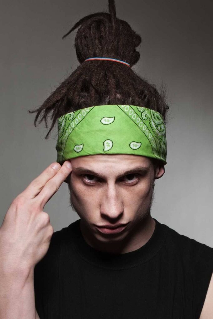 A man with a green bandana on his head and Bun dreadlocks.