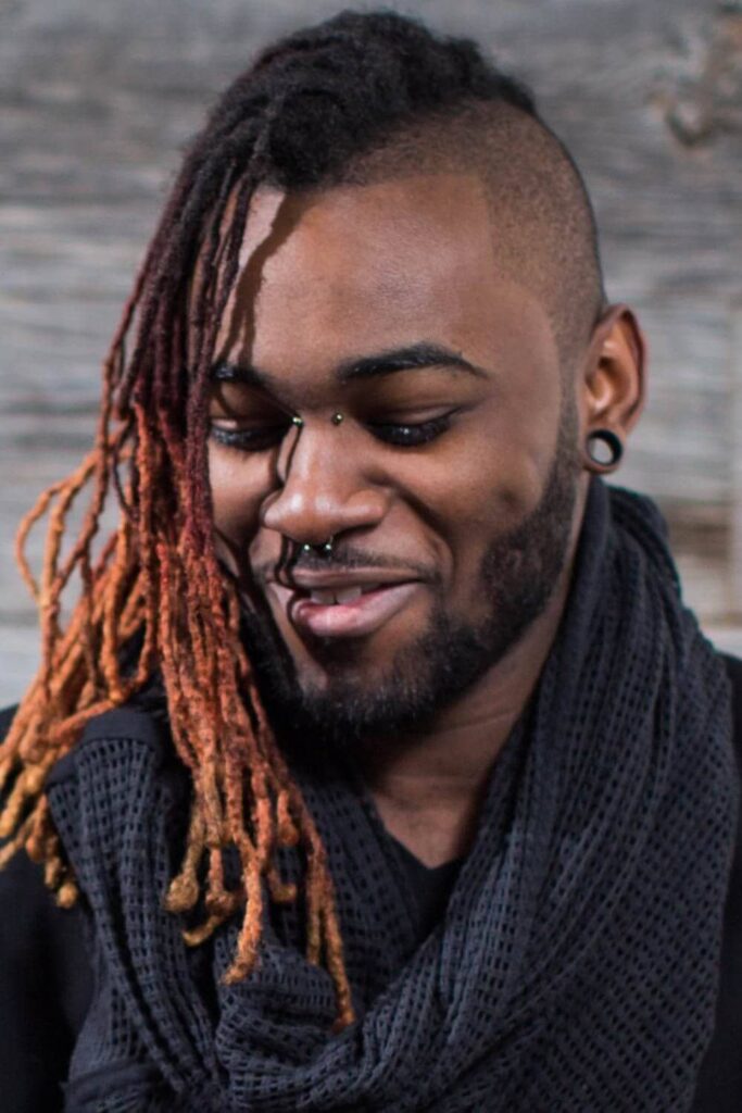 The man’s hair is styled in a unique way with half of his hair shaved and the other half styled in dreadlocks. Dreadlocks are a popular hairstyle for men and are created by twisting sections of hair together