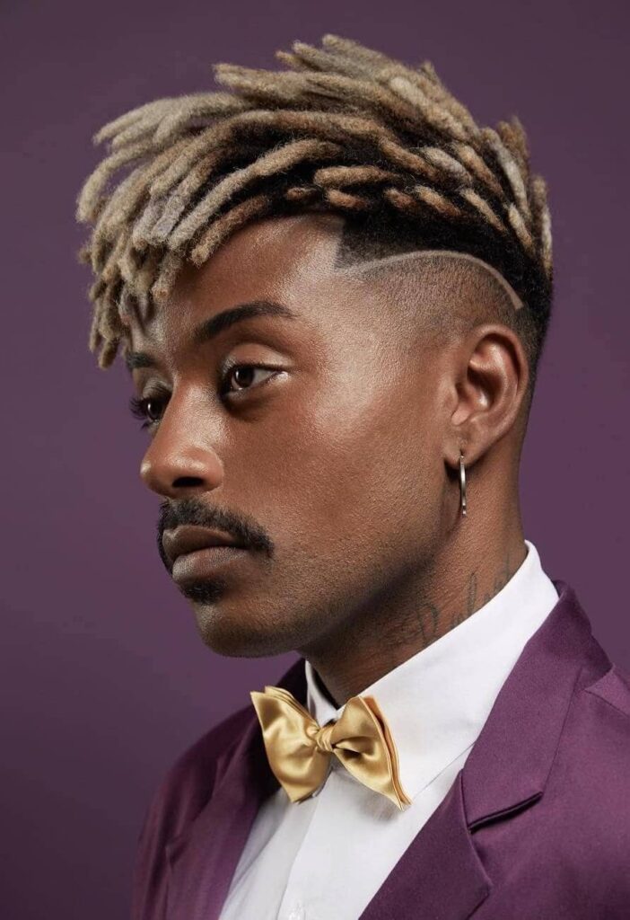 A man with loc styles fused with tramlines with short blonde Dreadlocks in Purple background.
