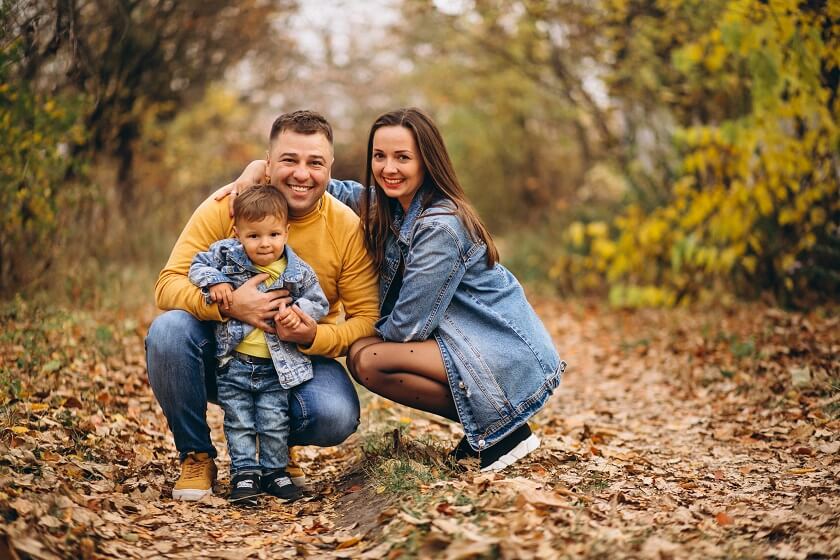 family with little son in autumn park wearing deniem and yellow Tones