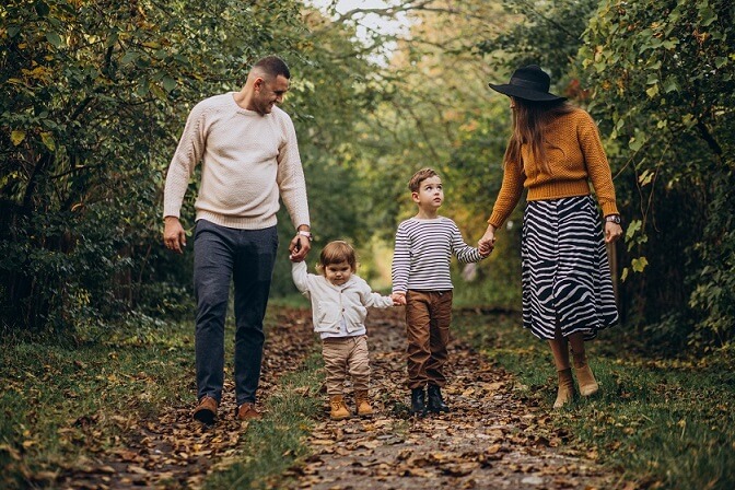 family walking through apple tree farm with pose and pastel tone outfits