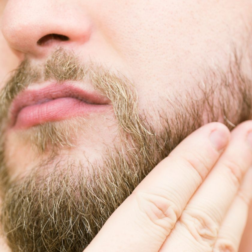 Brushing beard with hand after trimming